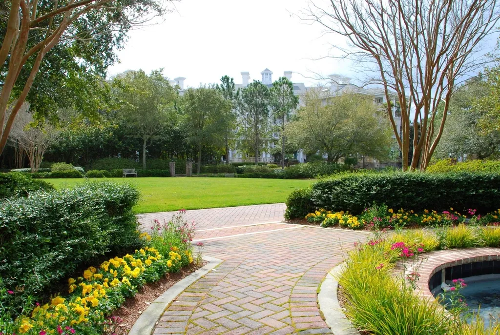 Landscaped yard with a curved paver walkway, flower beds, and trimmed hedges