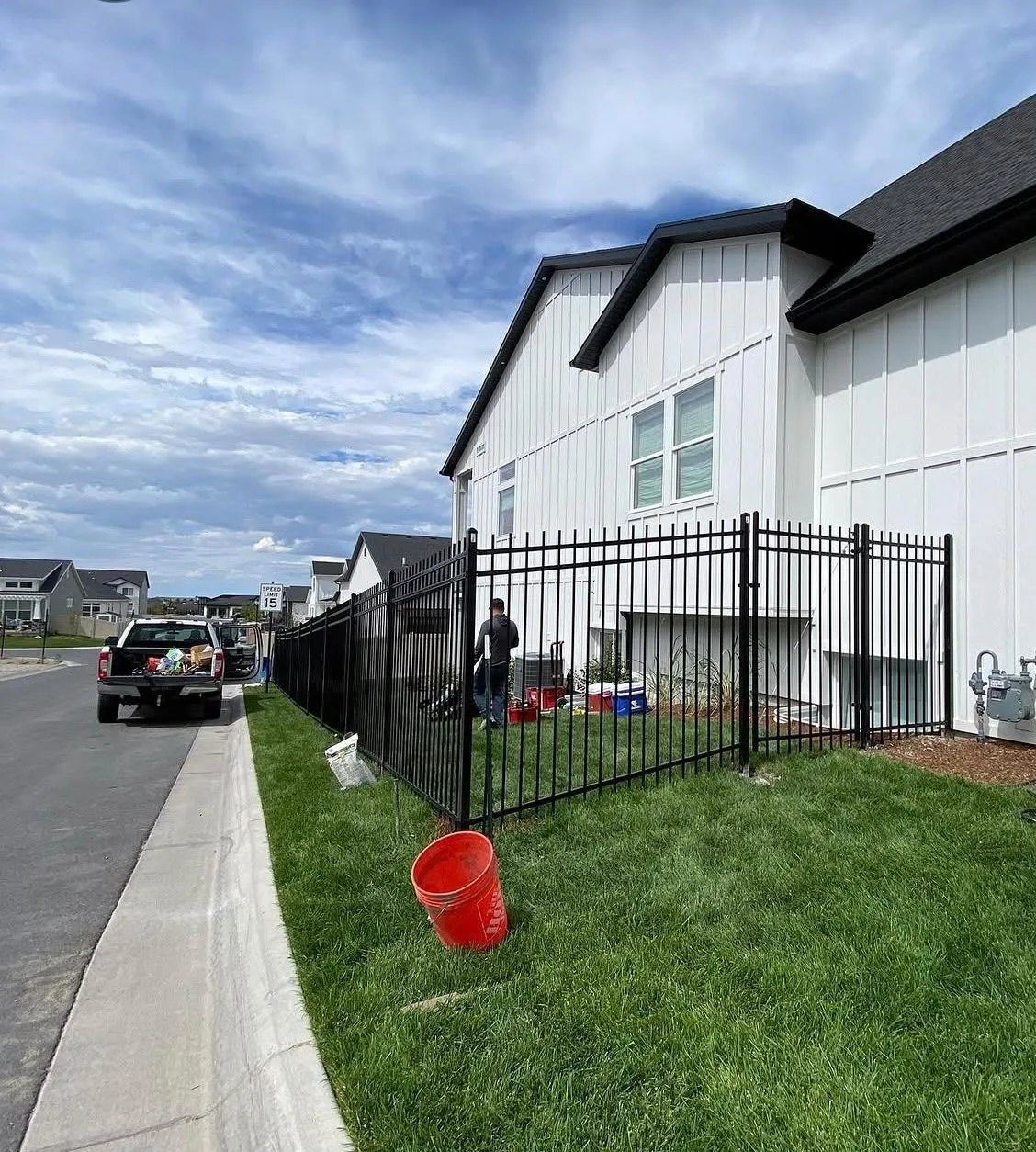 Black aluminum fence being installed along the side yard of a new home