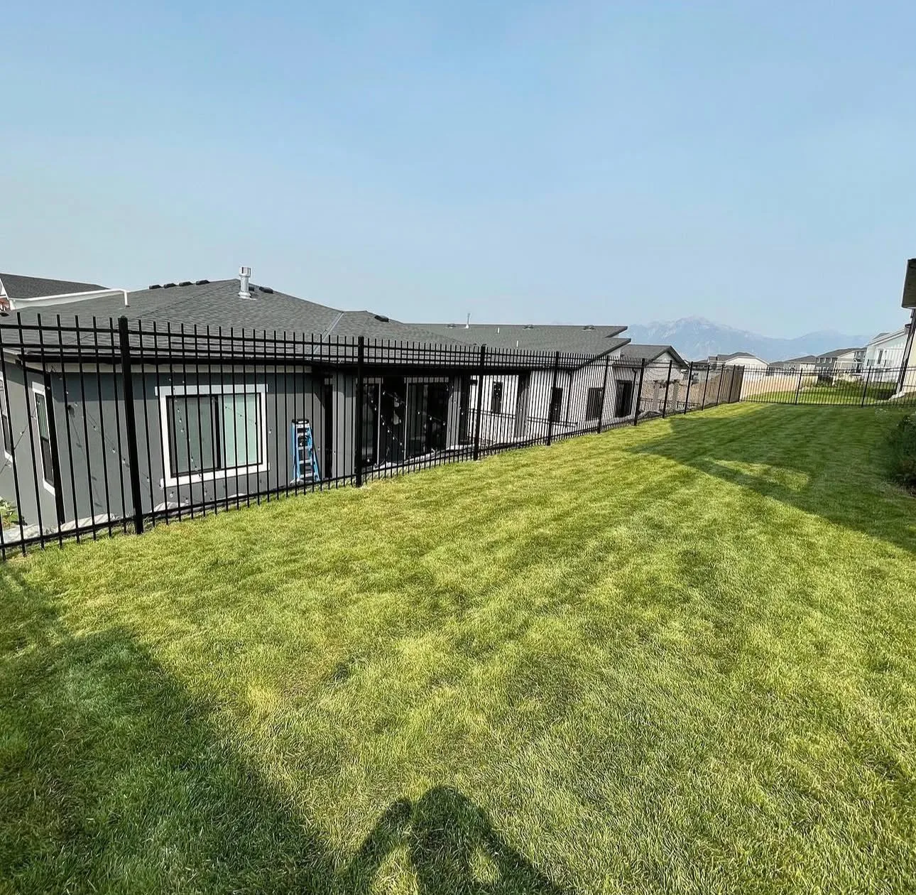 Black aluminum fence along a green backyard lawn with mountain views