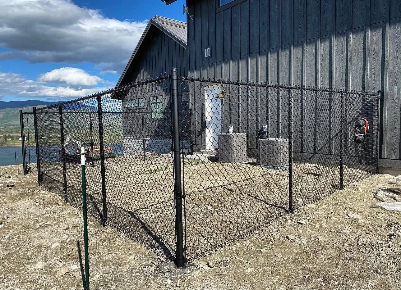 Black vinyl-coated chain link fence around the side yard of a new home
