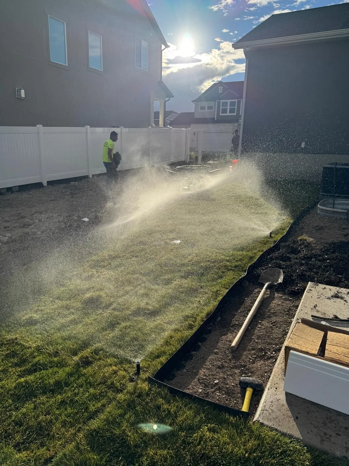 Pop-up sprinklers watering newly installed sod while the crew works
