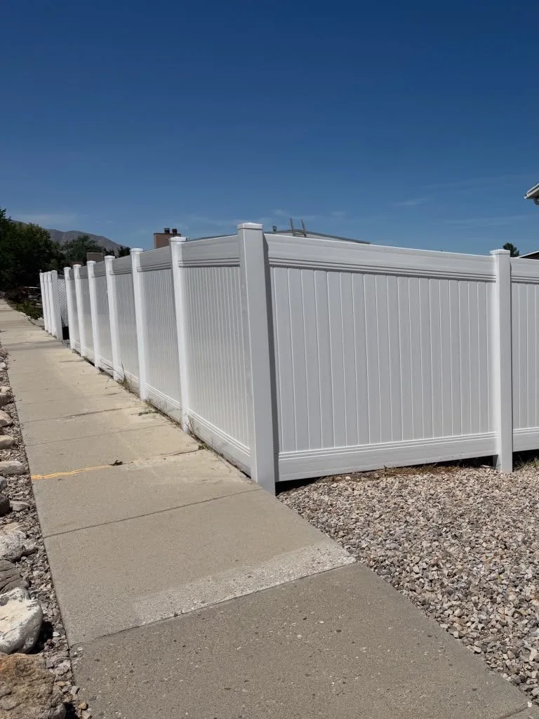 White vinyl privacy fence running along a sidewalk