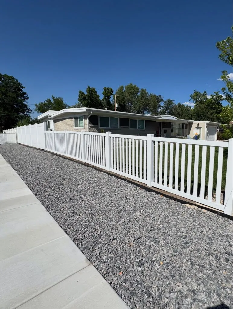 White vinyl semi-privacy fence along a front yard with a gravel border