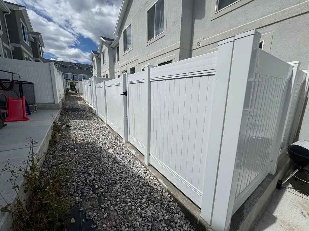 White vinyl privacy fence with a gate along a townhome side yard