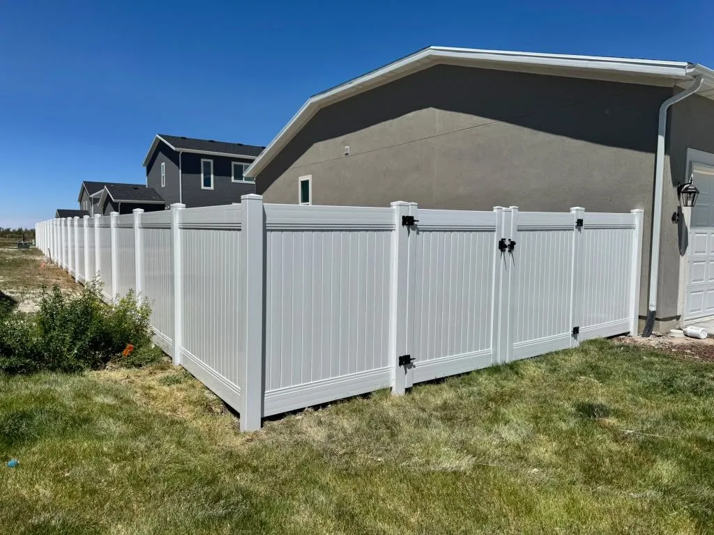 White vinyl privacy fence with a double gate next to a home