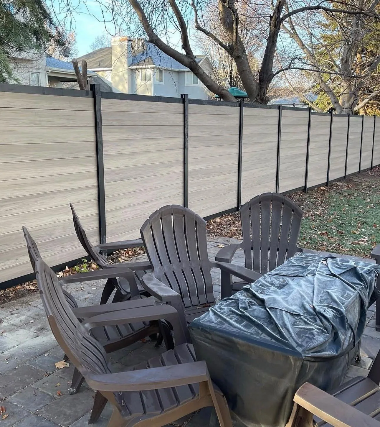 Long horizontal woodgrain privacy fence with black posts in a backyard